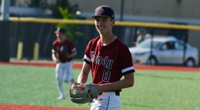 Sandy baseball player Brayden Sievertsen, wearing a red jersey, smiles on the baseball field